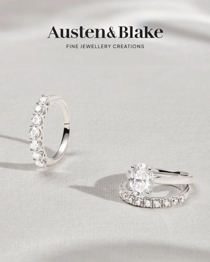 Two Austen & Blake diamond engagement rings on ivory fabric — oval solitaire and pavé eternity band