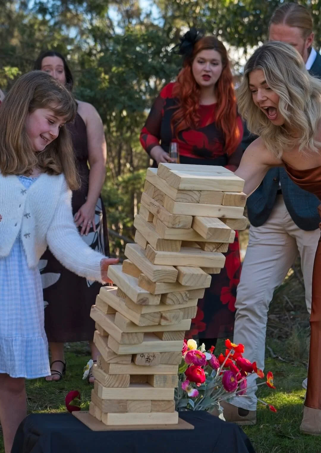Wedding guests laughing and playing giant Jenga at an outdoor reception, hired by The Party Isle