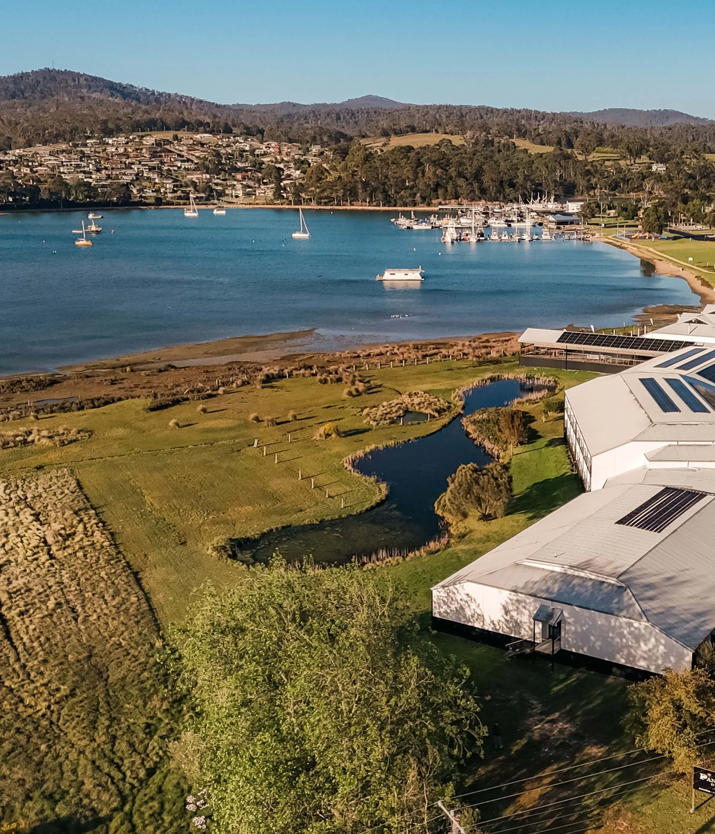 Aerial view of The Panorama Hotel beside a calm bay with moored boats and marina, St Helens East Coast Tasmania elopement venue