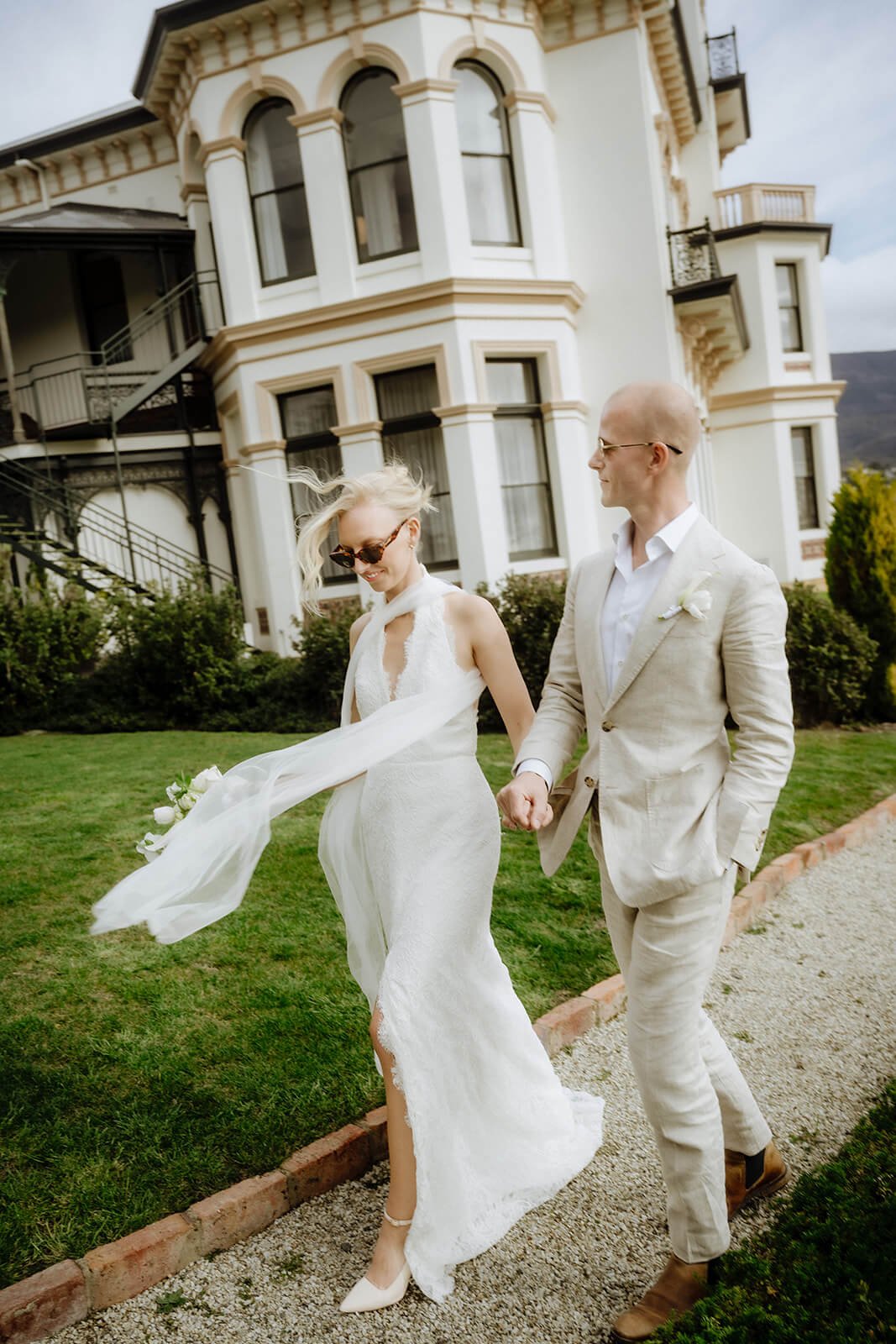 Bride and groom walking hand in hand past the ornate Victorian facade at Maylands Lodge, elopement wedding