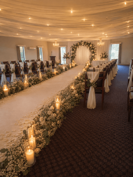 Indoor wedding ceremony aisle at The Panorama Hotel lined with candles and greenery, leading to a floral arch, East Coast Tasmania