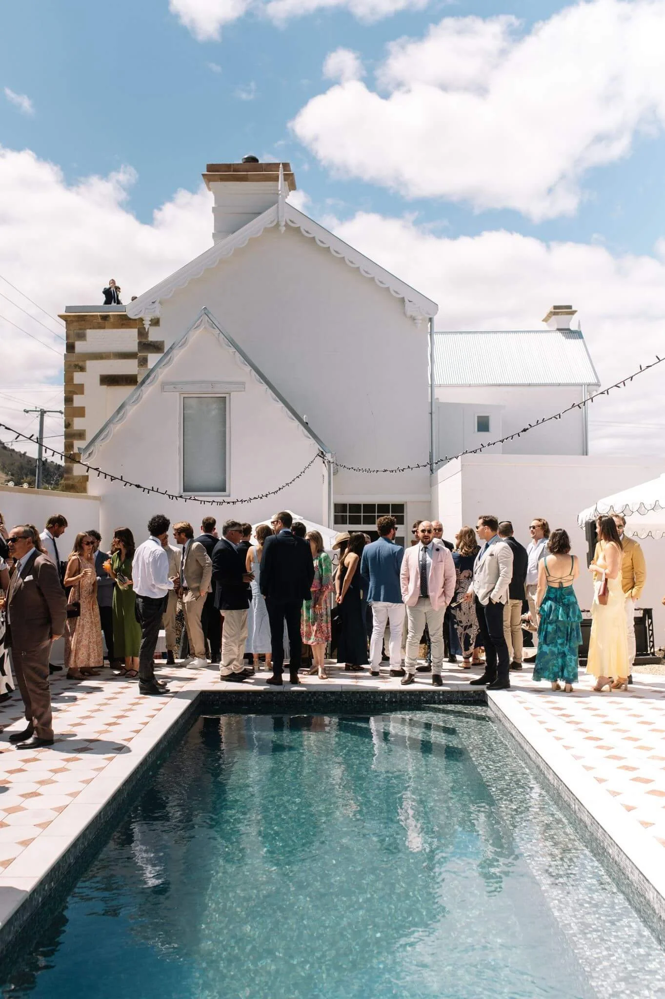 Wedding guests mingling poolside at Palazzo Campania, heritage building backdrop, Southern Tasmania