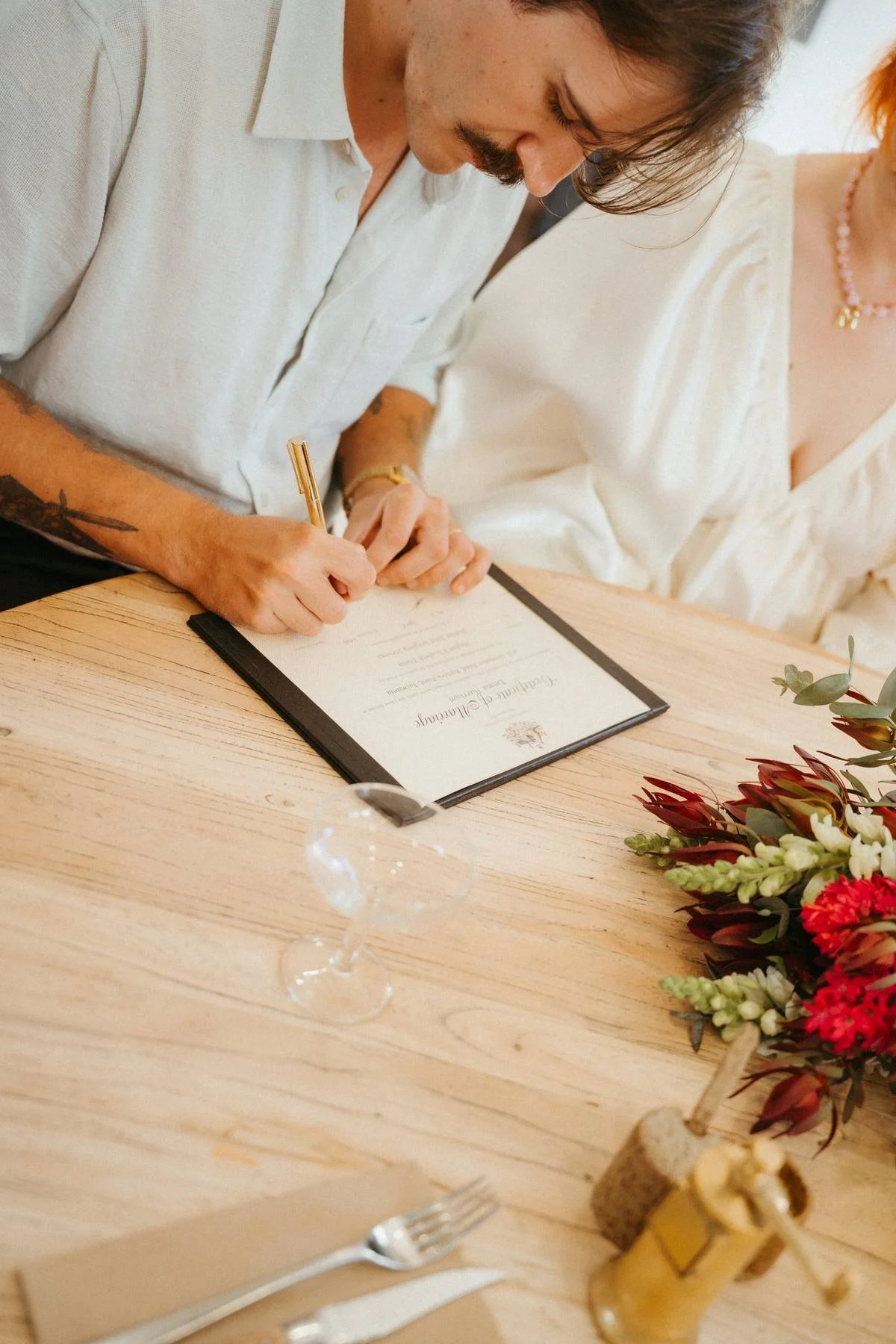 Couple signing their legal marriage certificate during a simple registry-style wedding ceremony in Hobart