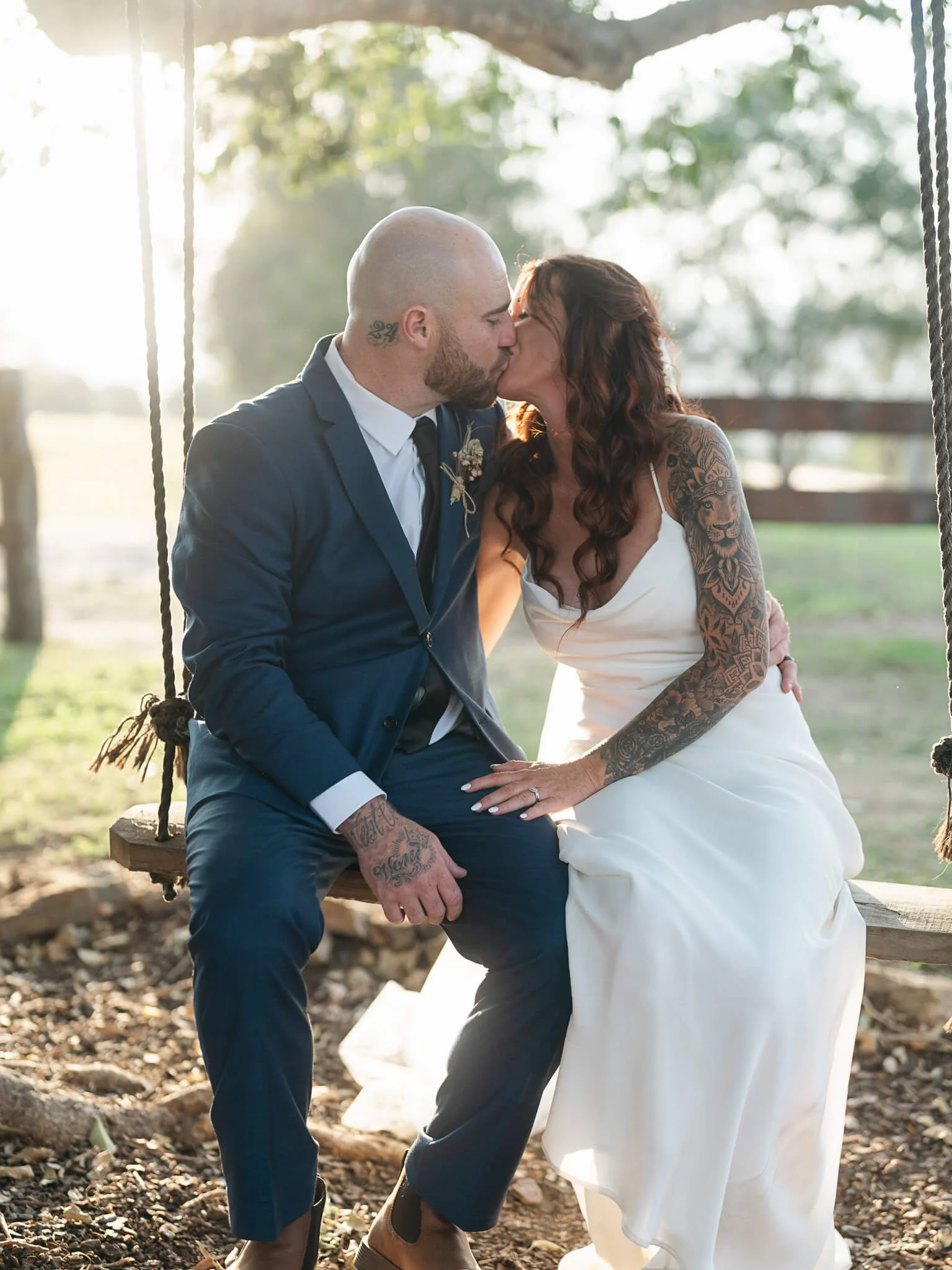 a couple kissing on their wedding day while sitting on a garden swing