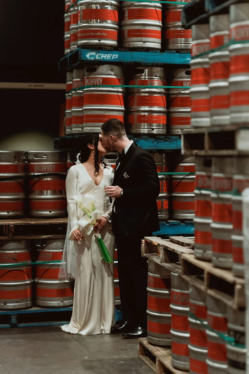 a wedded couple kissing inside a barrel ageing room