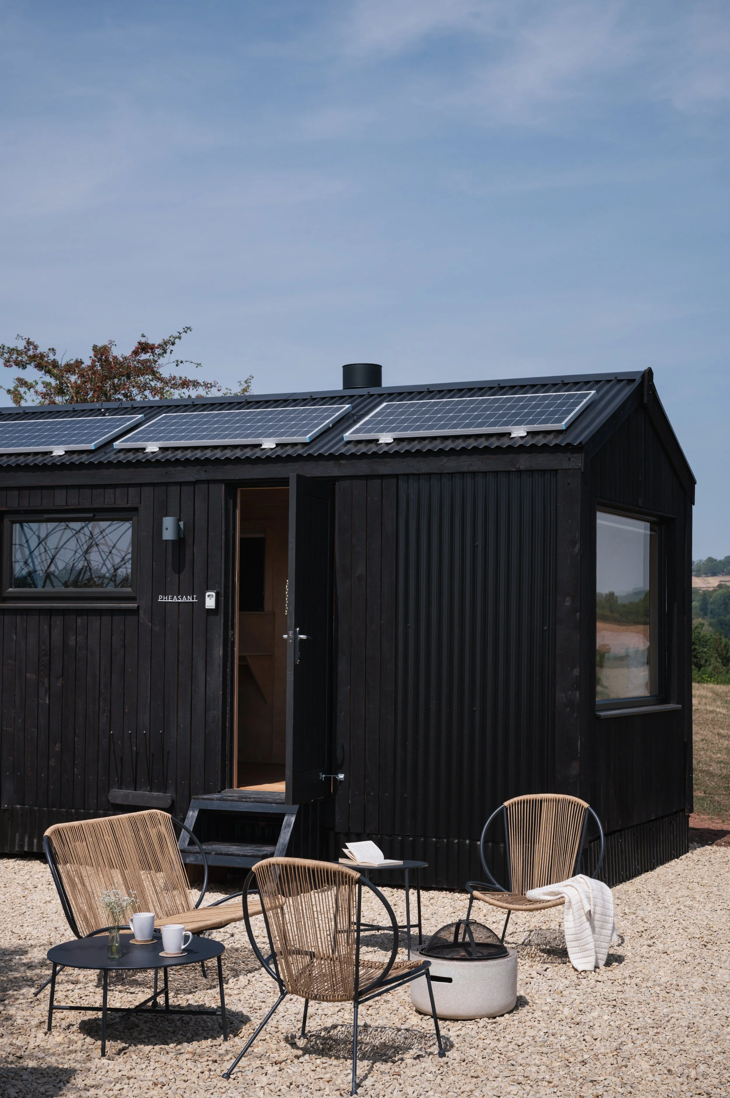 Off grid Tiny house with solar panels and outdoor seating, offering eco-friendly accommodation in the countryside.