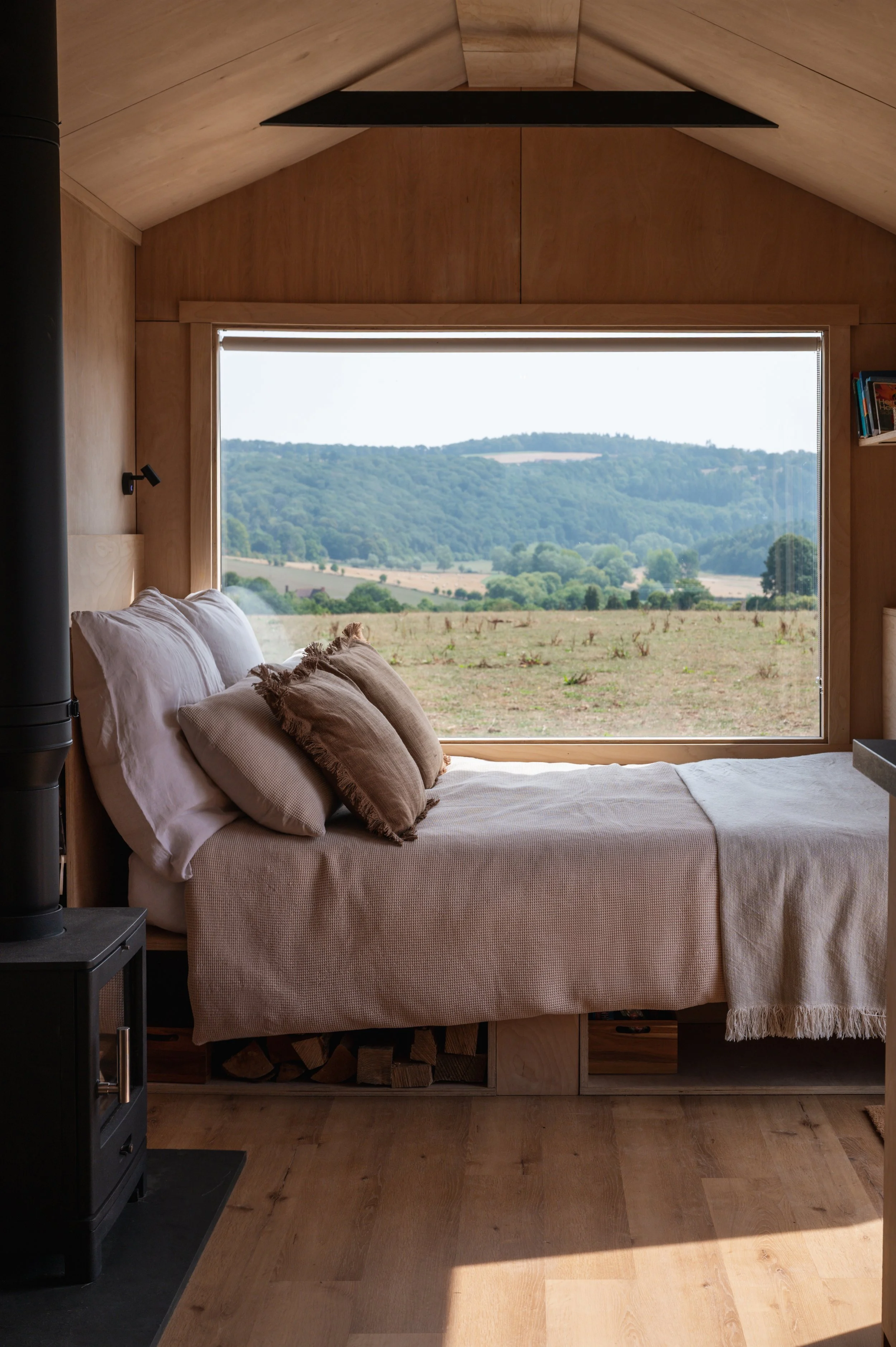 Relax in a beautifully designed tiny house featuring a comfortable bed, log burner, and panoramic countryside views. Perfect for a luxury glamping escape surrounded by nature.