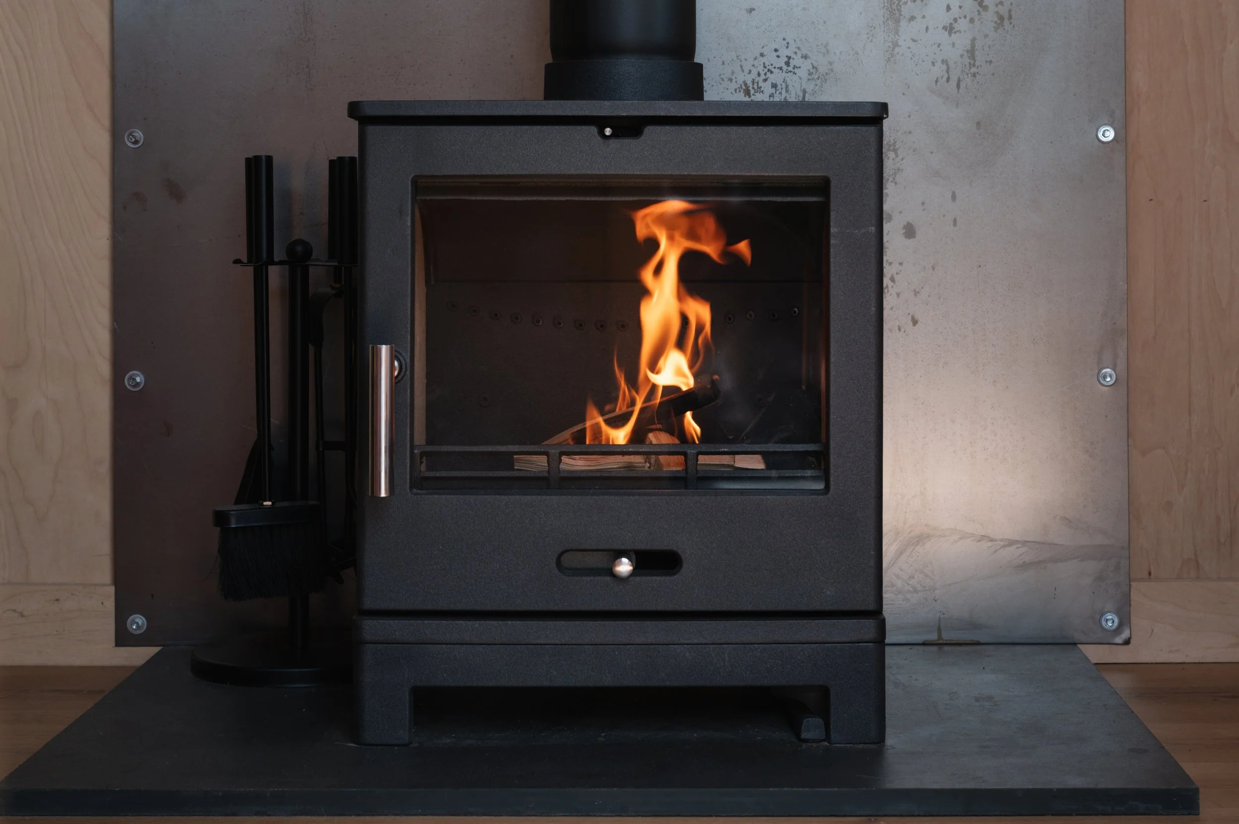 Close-up of a modern wood-burning stove with a cozy fire, adding warmth and rustic charm to a tiny house retreat.