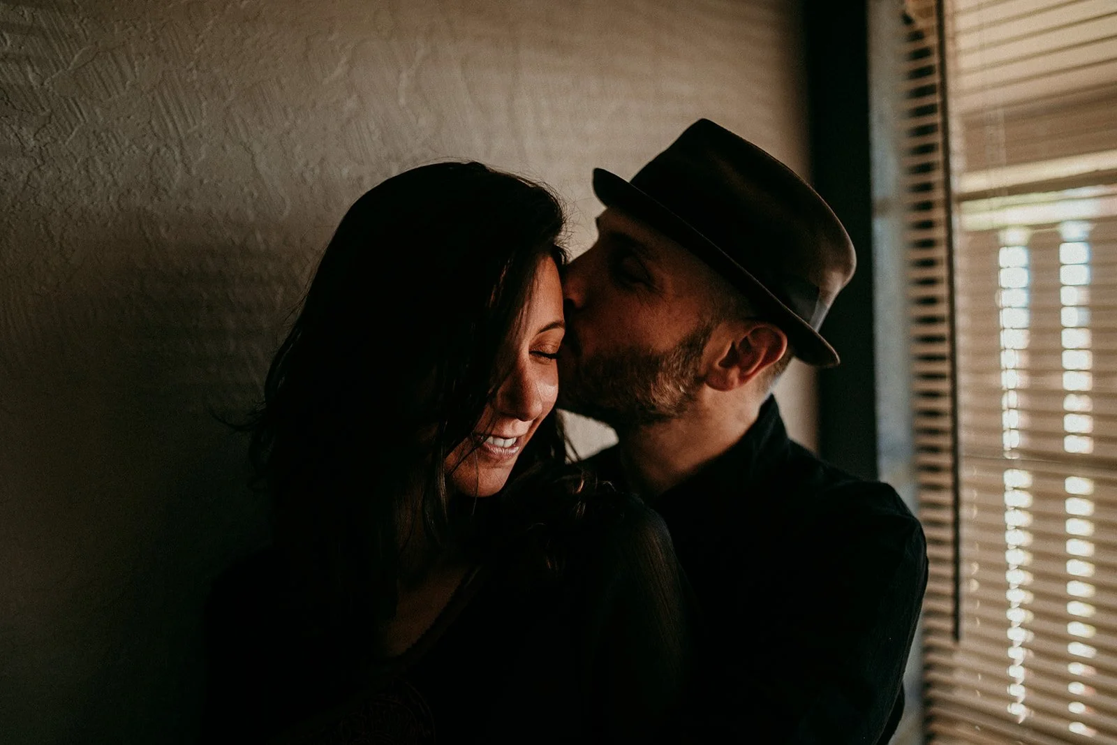 Couple shares an intimate kiss, soft indoor lighting.