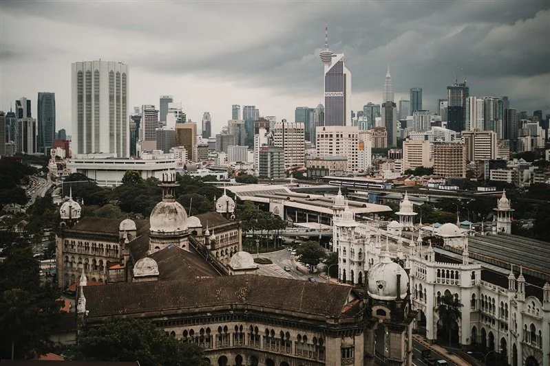 City skyline with a mix of modern skyscrapers and historical buildings under cloudy sky in Malaysia