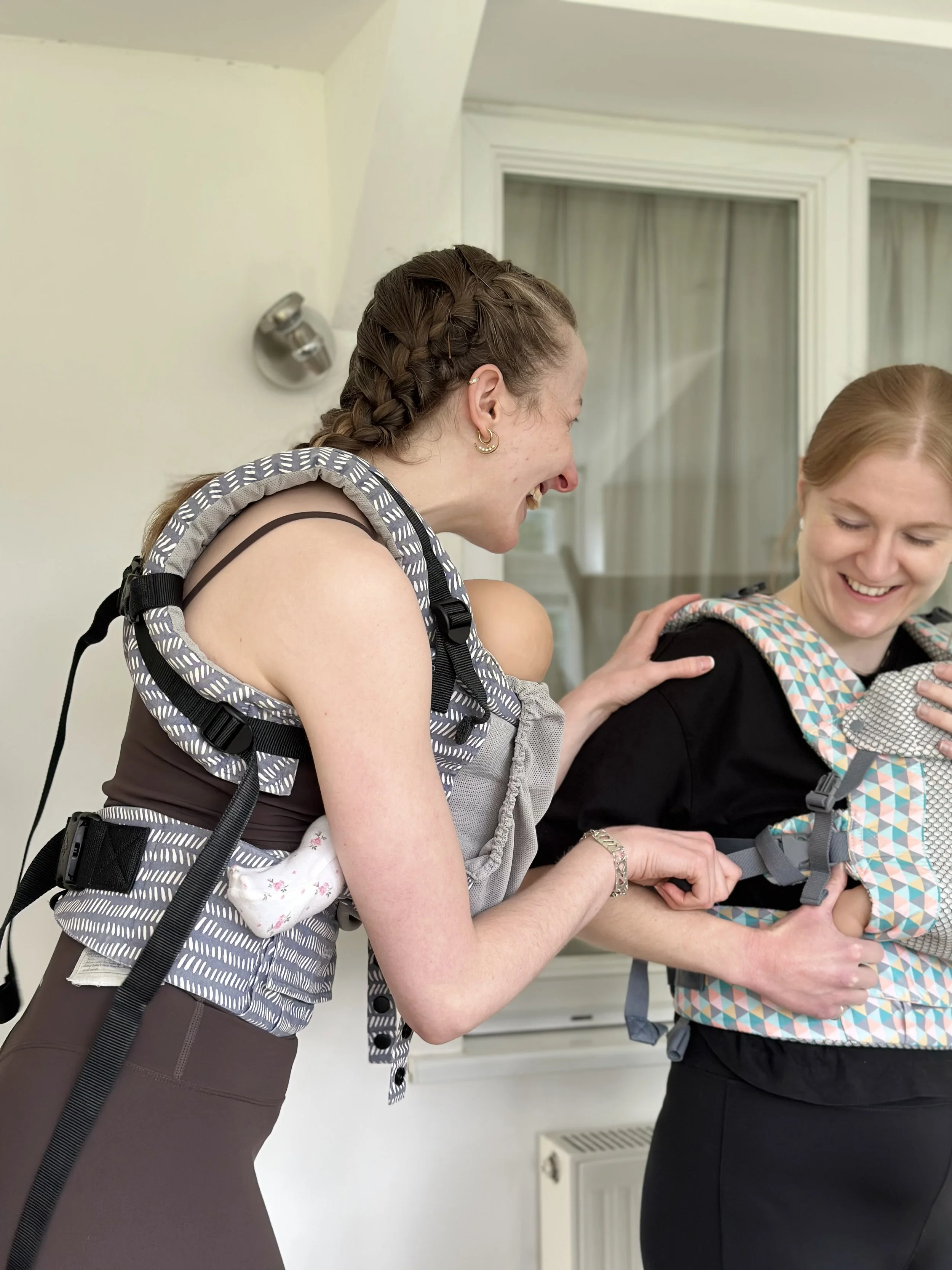 Two women carrying babies in slings