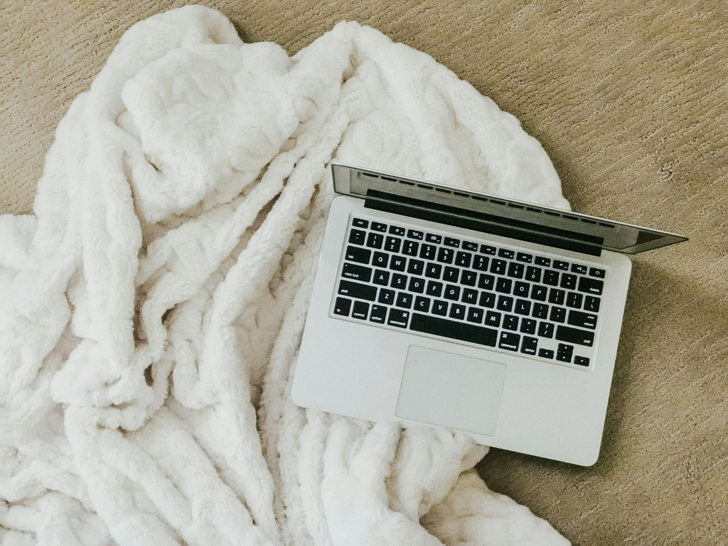 Computer sitting in white blanket.