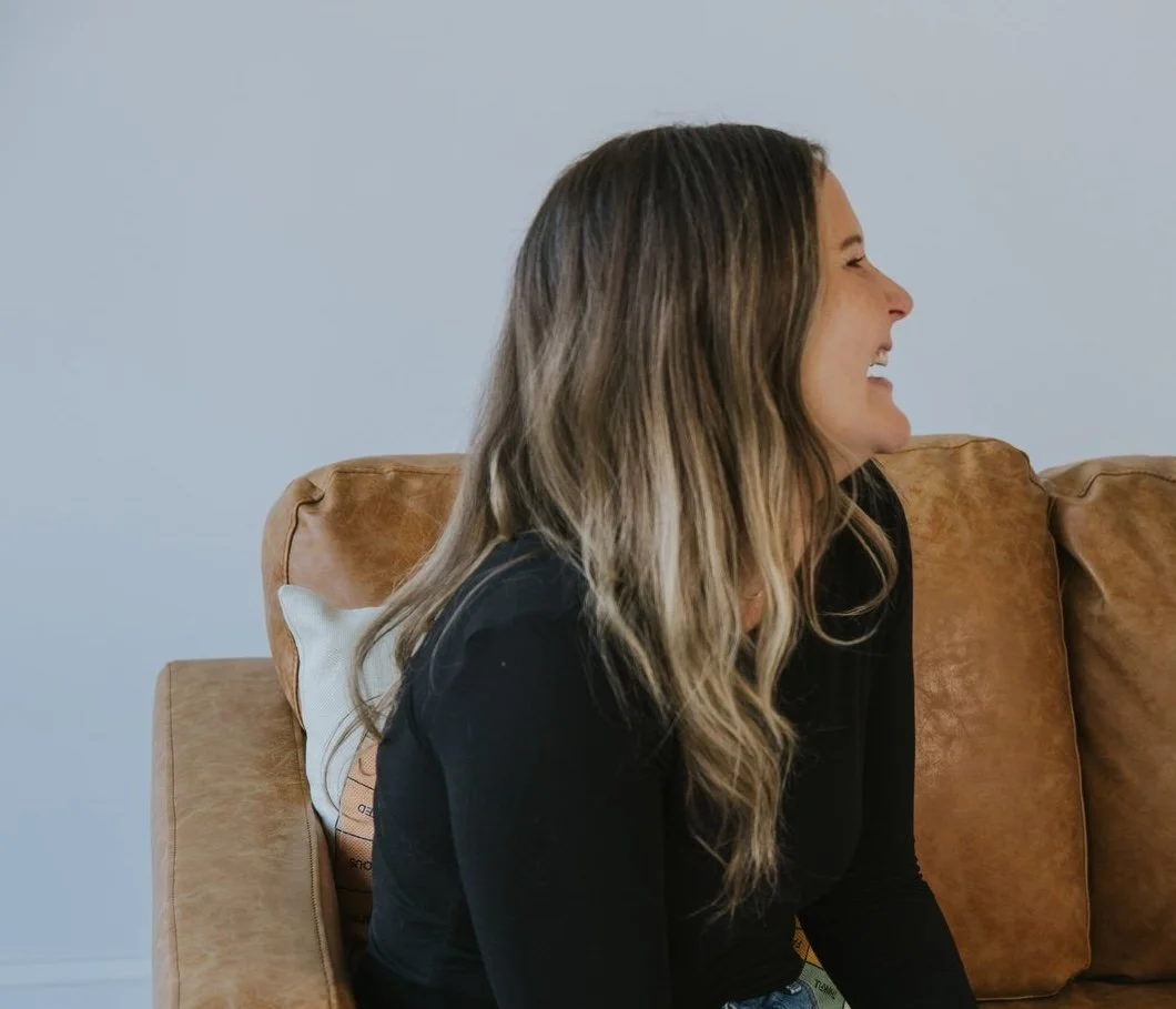Adrienne Hayes, LMFT, Raleigh therapist laughing on a couch