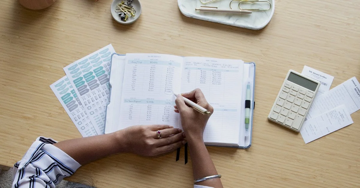 Woman writing in planner in modern desk setting.