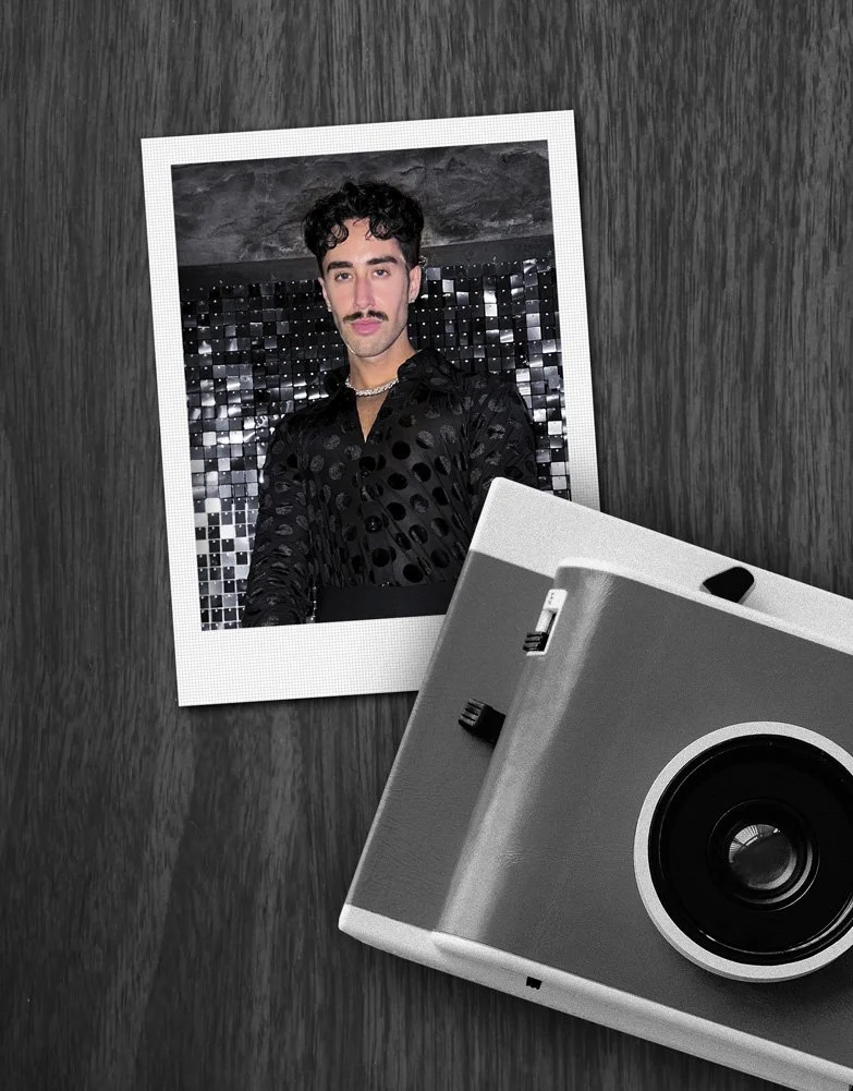 Polaroid photo of Alexander on dark wood background with camera on top