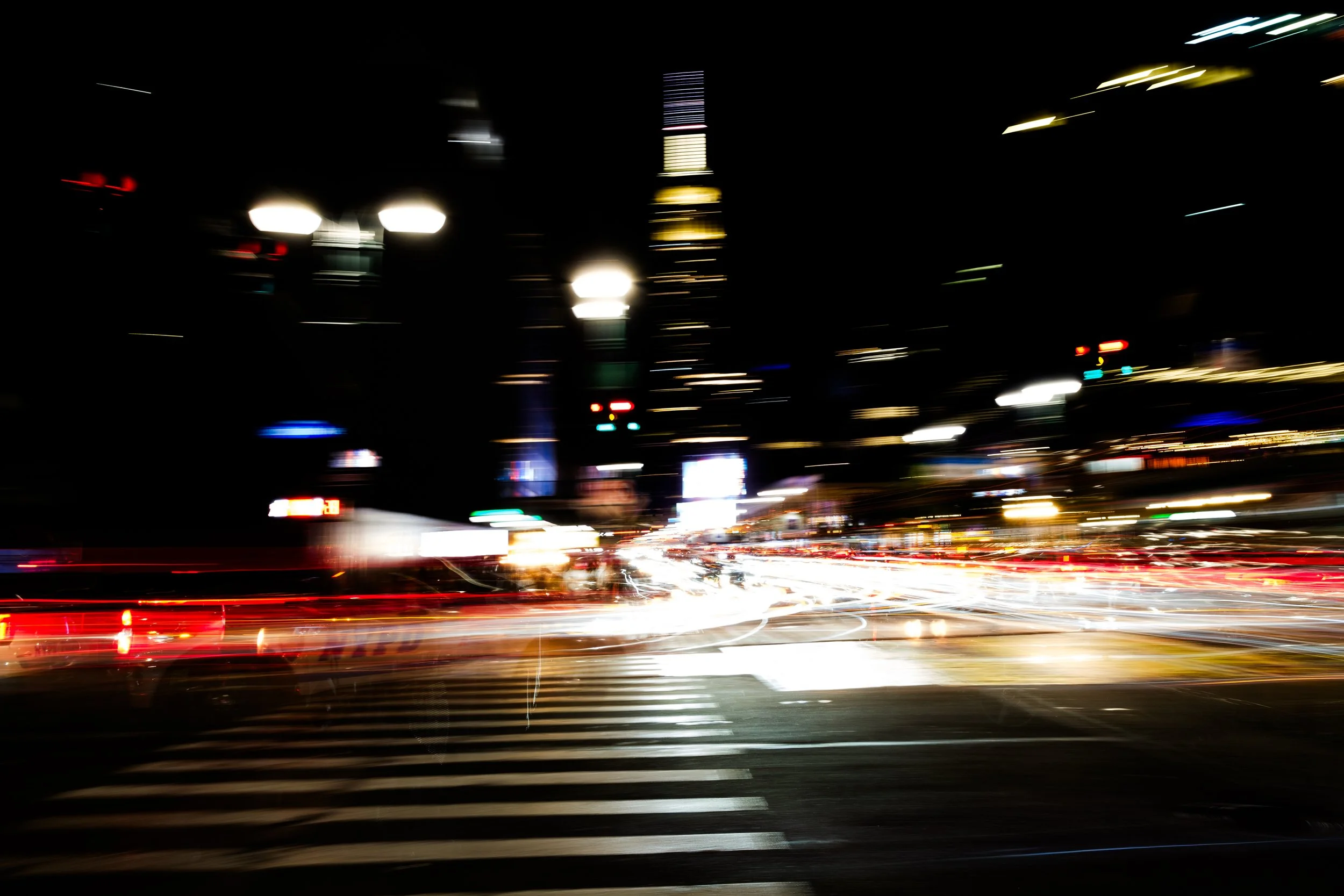 Long exposure photo of city streets at night with streaks of car lights and blurred building lights.