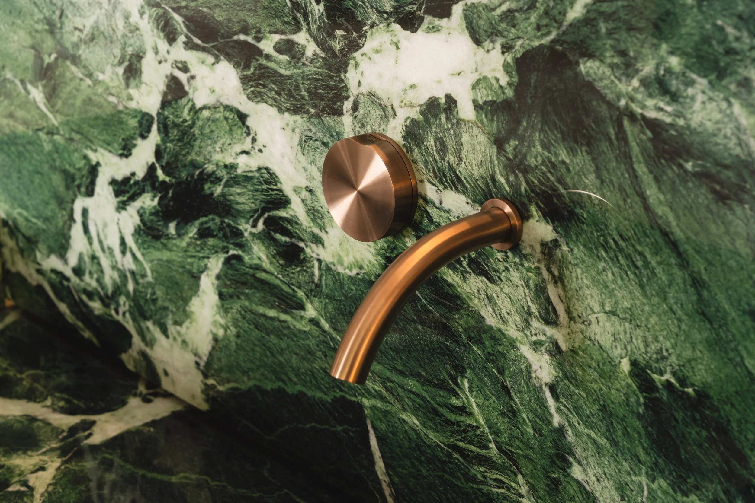 Close-up of the Verde St Denis sink, showing its natural green hue and smooth, sculpted surface.