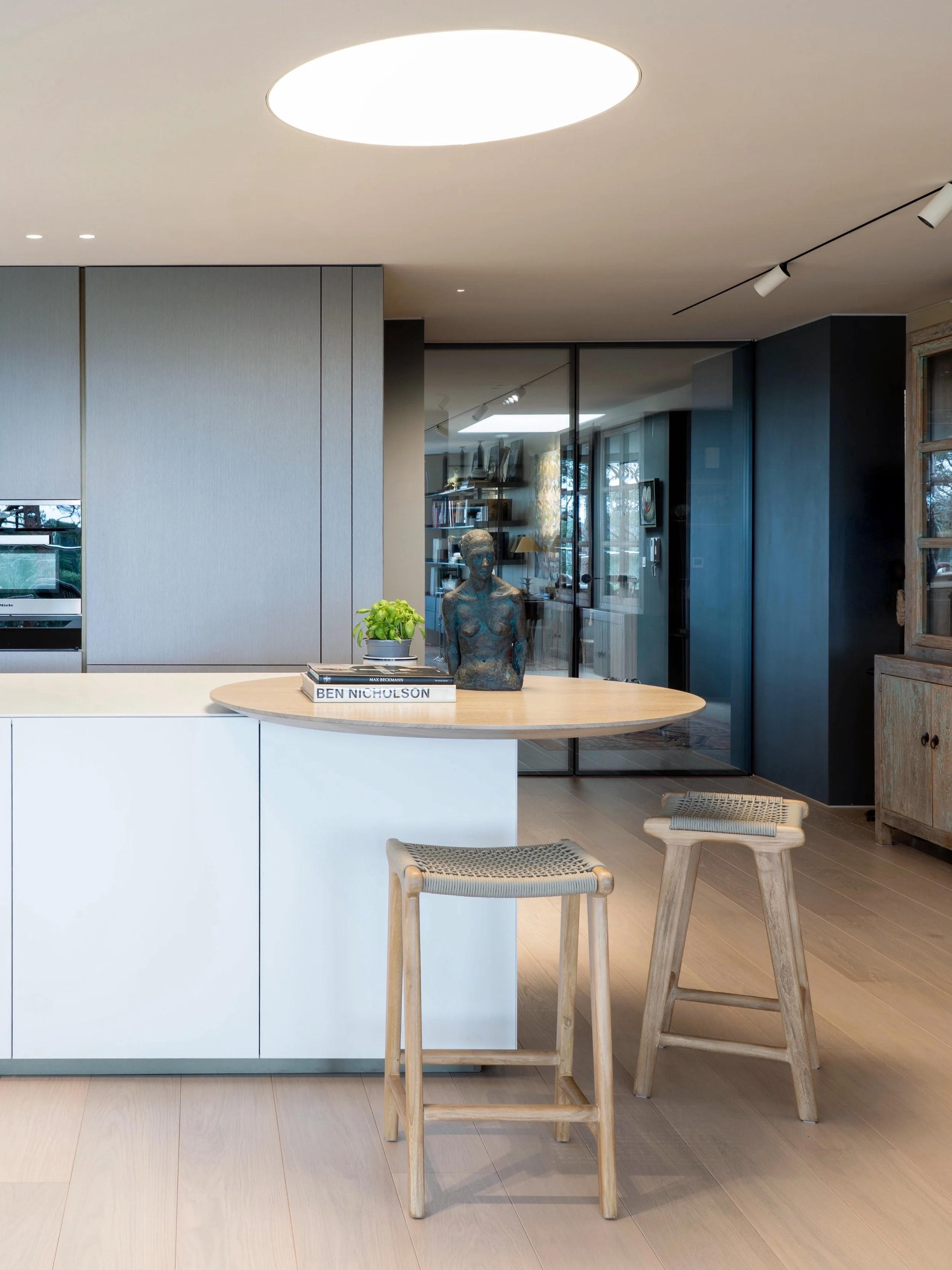 A kitchen should do more than provide a place to cook; it should quietly guide how a space is experienced. 

The treetop views are the focal point on this project, so we deliberately avoided a pendant light, using a circular ceiling light to echo the