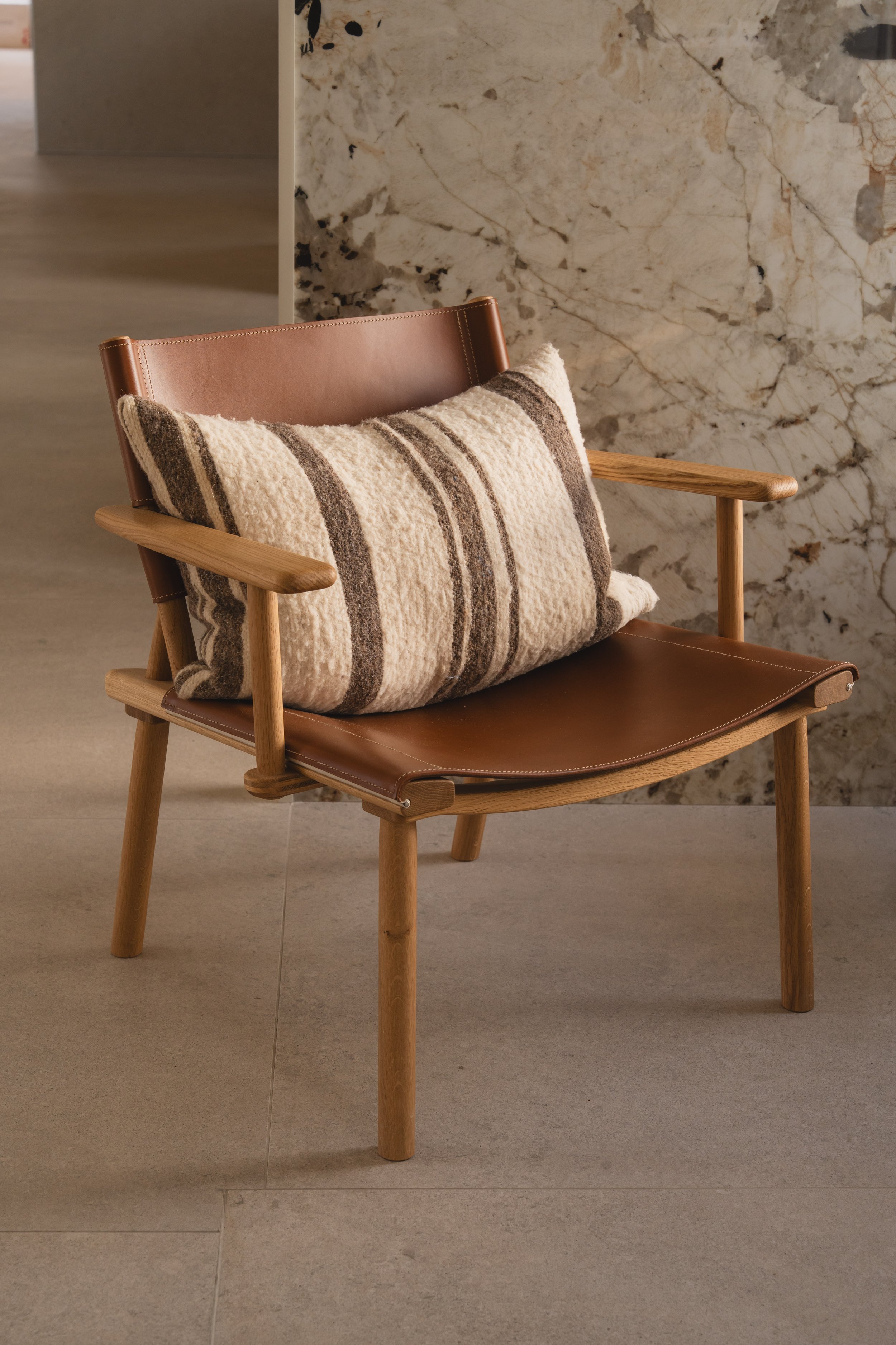 Minimalist designer lounge chair by Nikari with solid wood frame and natural upholstery.