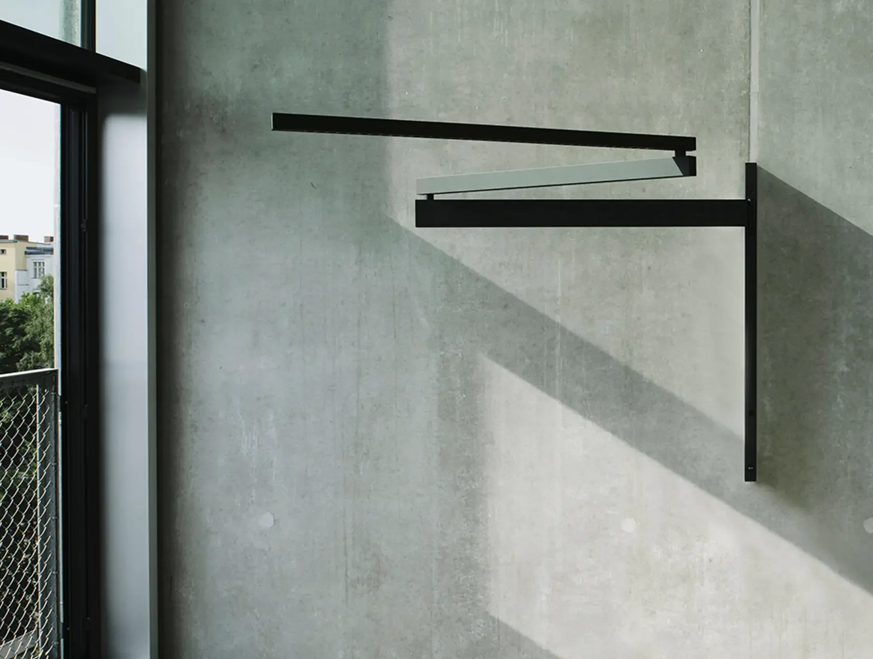 Black Flag wall light by Flos with extendable aluminium arm and minimalist industrial design in contemporary interior.