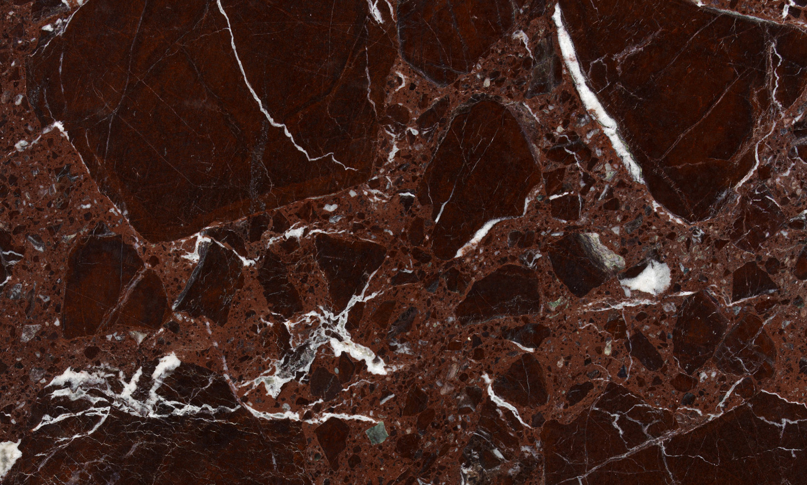 A close-up photograph of a polished red marble surface with white and black veining.