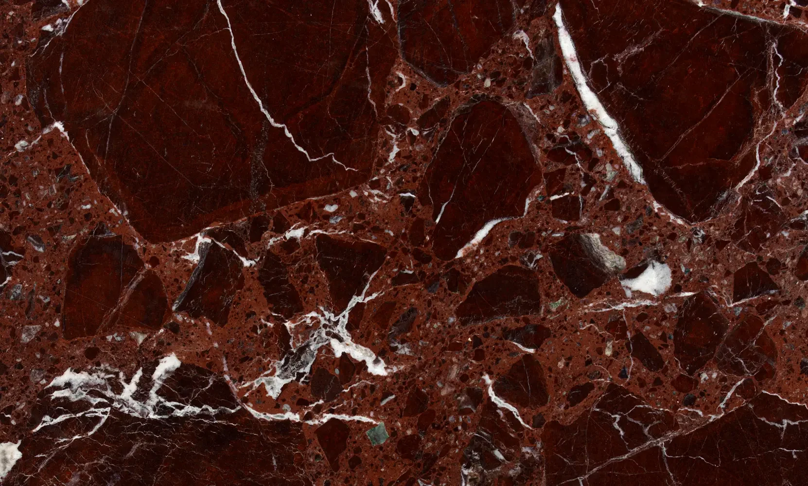 A close-up photograph of a polished red marble surface with white and black veining.