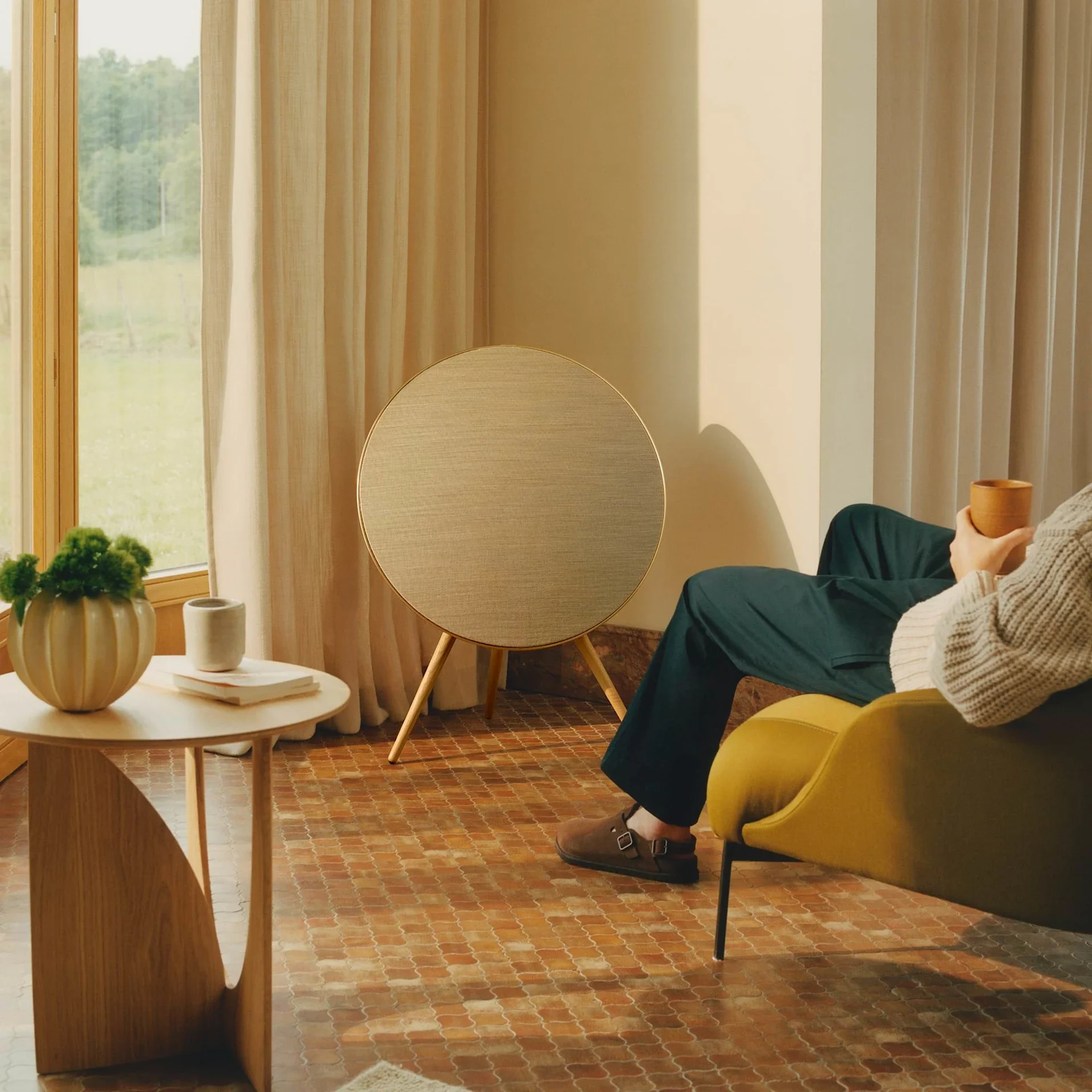 Freestanding Beosound A9 speaker with sculptural circular form in lounge area.
