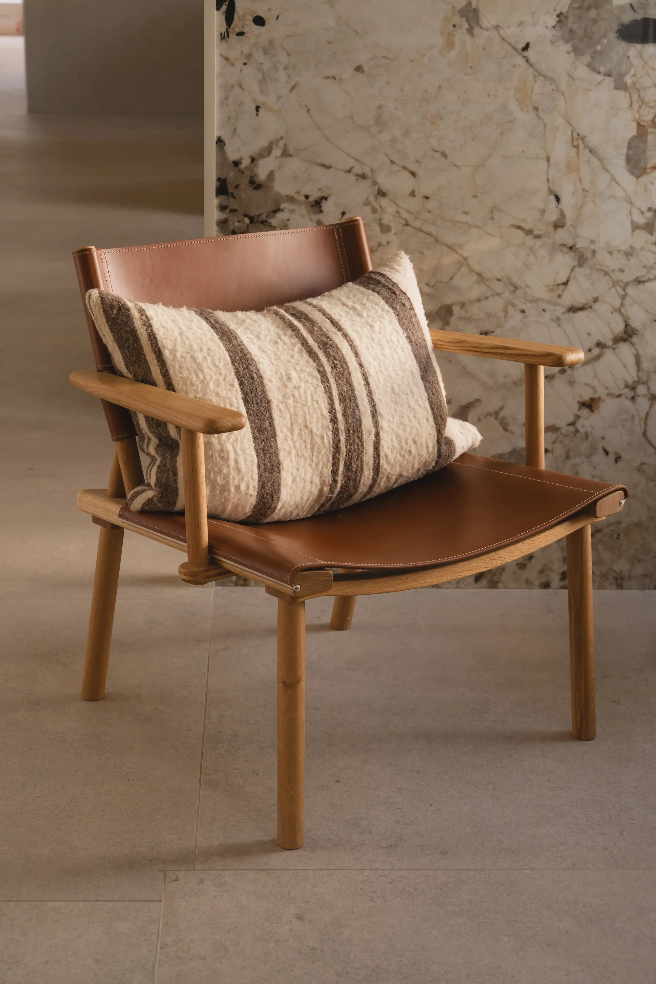 Minimalist designer lounge chair by Nikari with solid wood frame and natural upholstery.