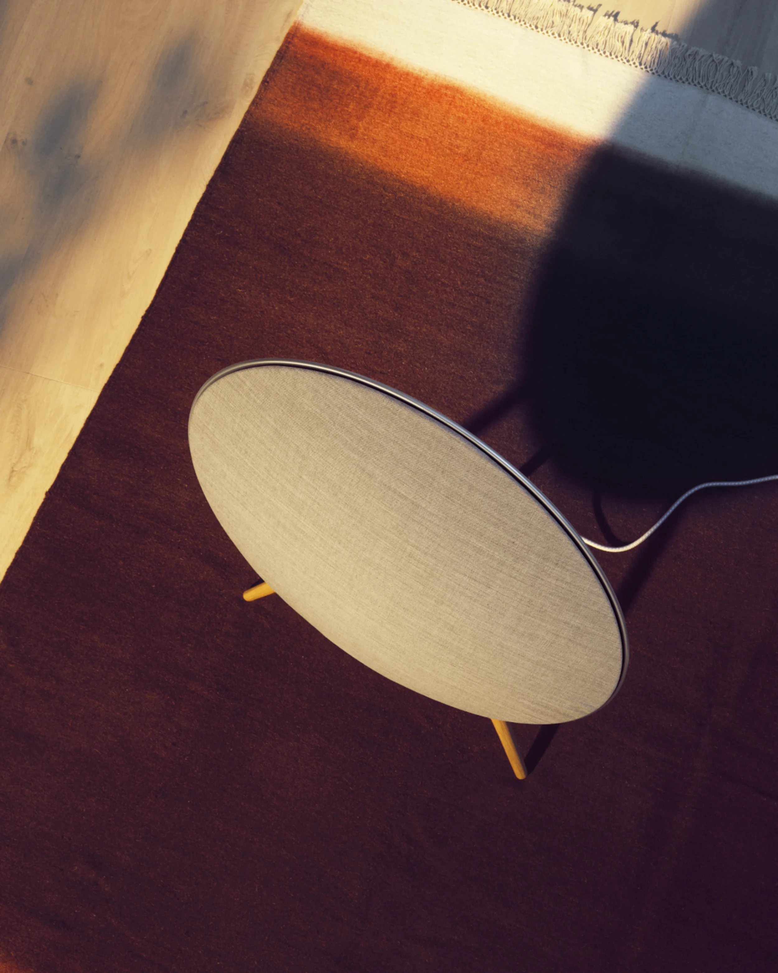 Bang & Olufsen A9 speaker with oak legs and tactile fabric in minimalist interior.