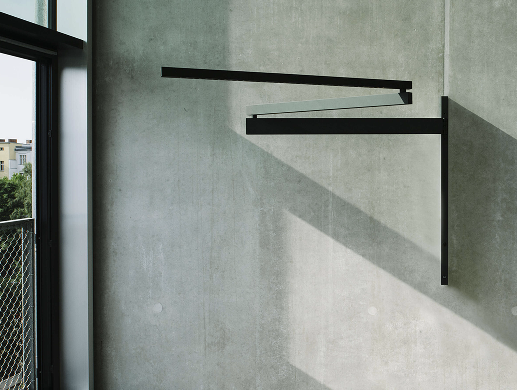 Black Flag wall light by Flos with extendable aluminium arm and minimalist industrial design in contemporary interior.