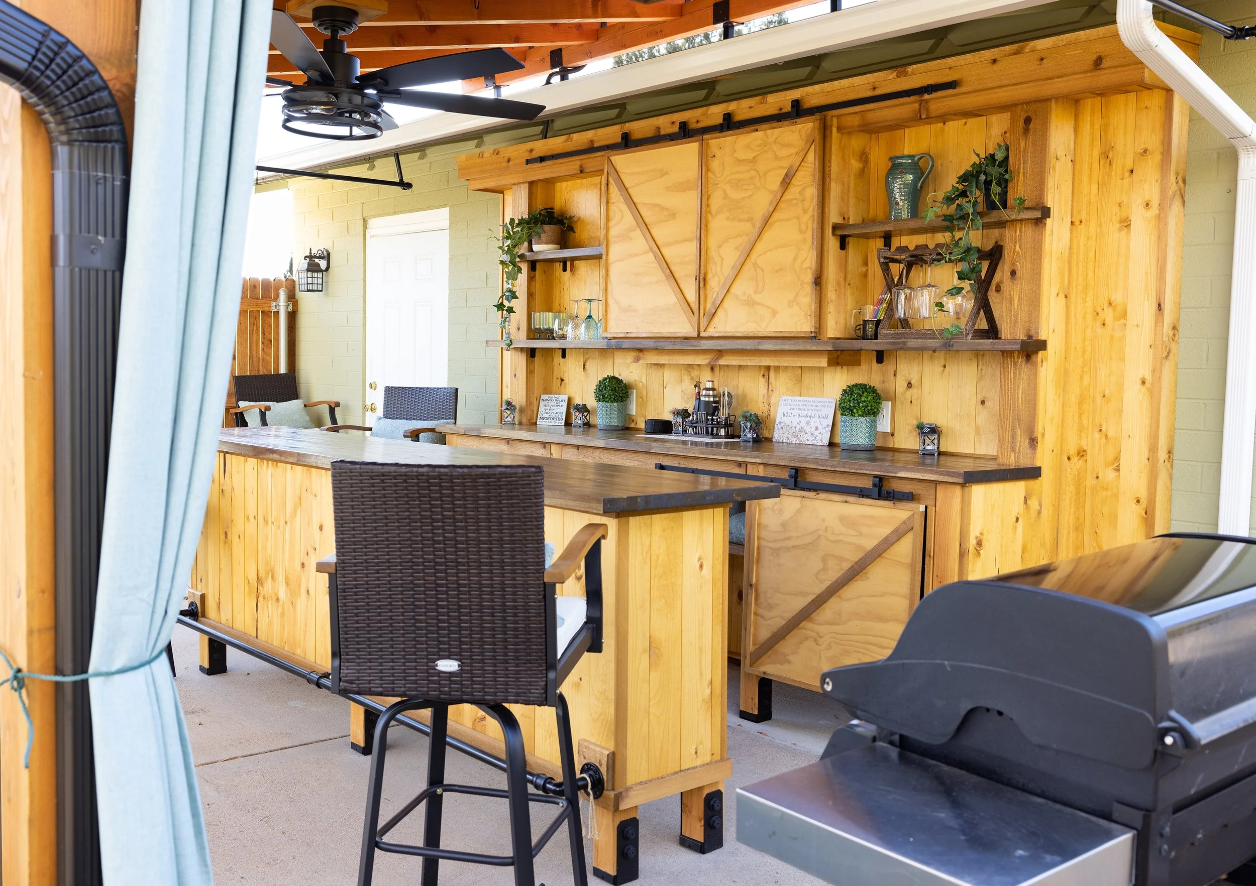 This outdoor patio bar is fully covered by the attached metal roofing and held securely by sturdy exposed beams.  The bar features stained and sealed butcher block, butcher block shelving, matte black hardware, functional barn door cabinets, multiple