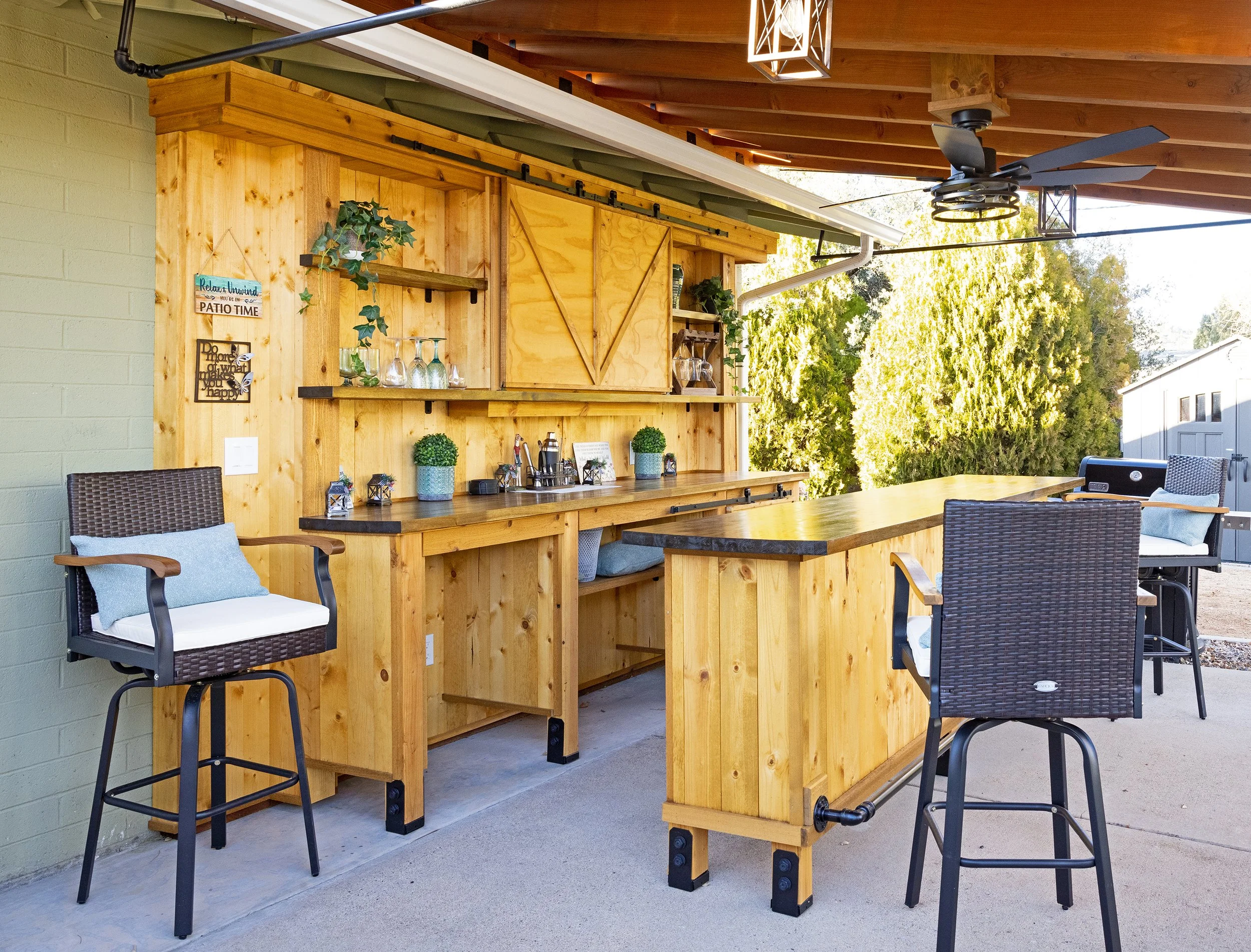 This outdoor patio bar is fully covered by the attached metal roofing and held securely by sturdy exposed beams.  The bar features stained and sealed butcher block, butcher block shelving, matte black hardware, functional barn door cabinets, multiple
