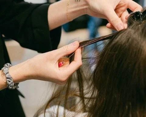 Stylist working on a client's hair with a sectioned strand