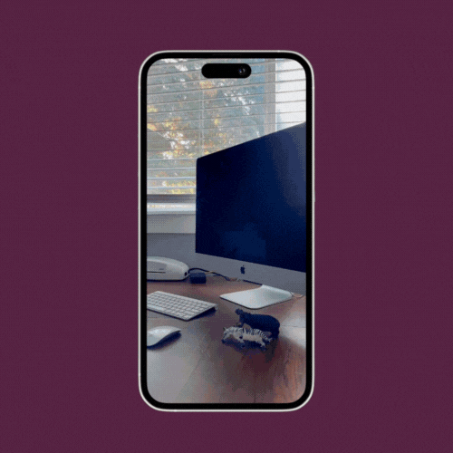 iPhone showing a reflection of a computer monitor and desk with a keyboard and mouse