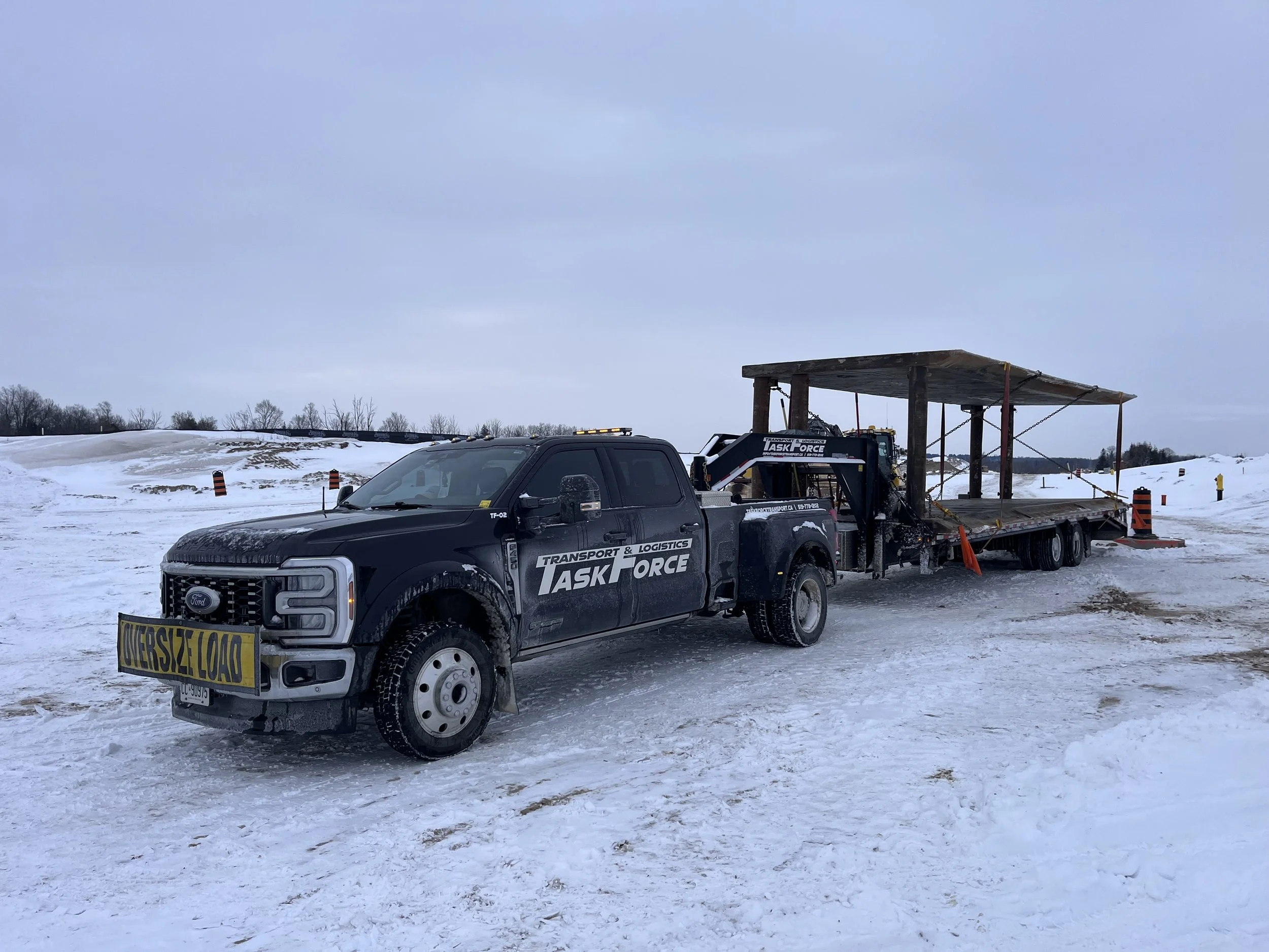 Task Force Transport & Logistics Ford F-450 hotshot truck transporting oversize cargo on a gooseneck flatbed trailer in Ontario, Canada.