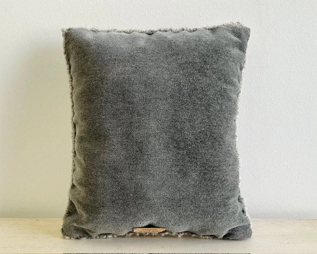 Back of pillow in soft gray wool fabric.