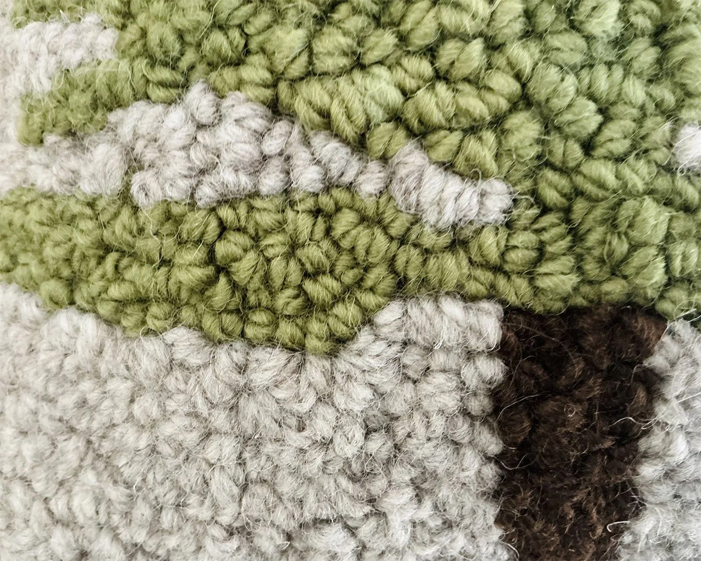 Detail of hand-hooked wool showing tree branches an textured ground.