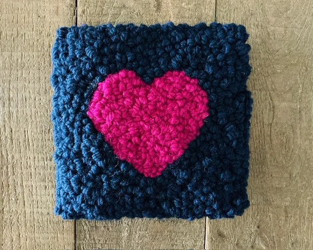 Hand-hooked wool panel with a bright pink heart on a navy wool ground.