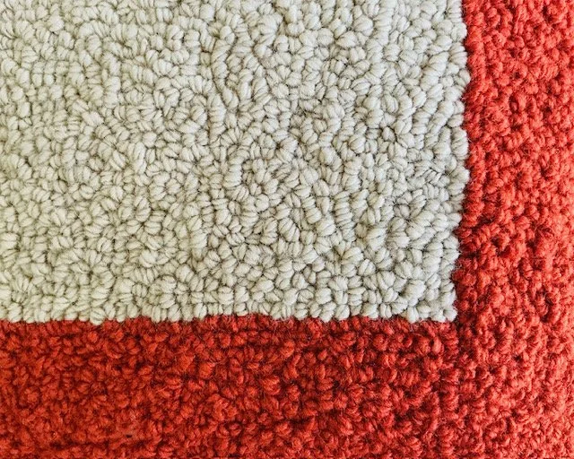 Detail of hand-hook wool texture forming the geometric lines.