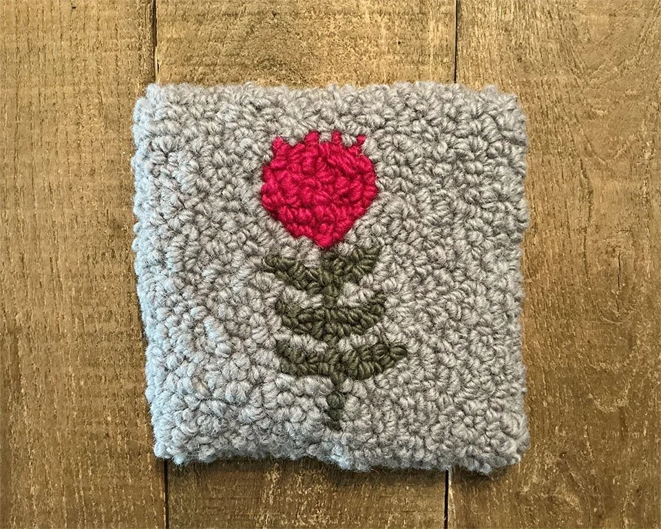 Hand-hooked wool panel in slate featuring stylized bright pink bloom with green stem.