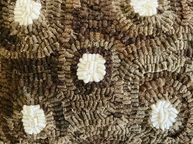 Detail of hand-hooked wool forming a flower motif on oak brown ground.