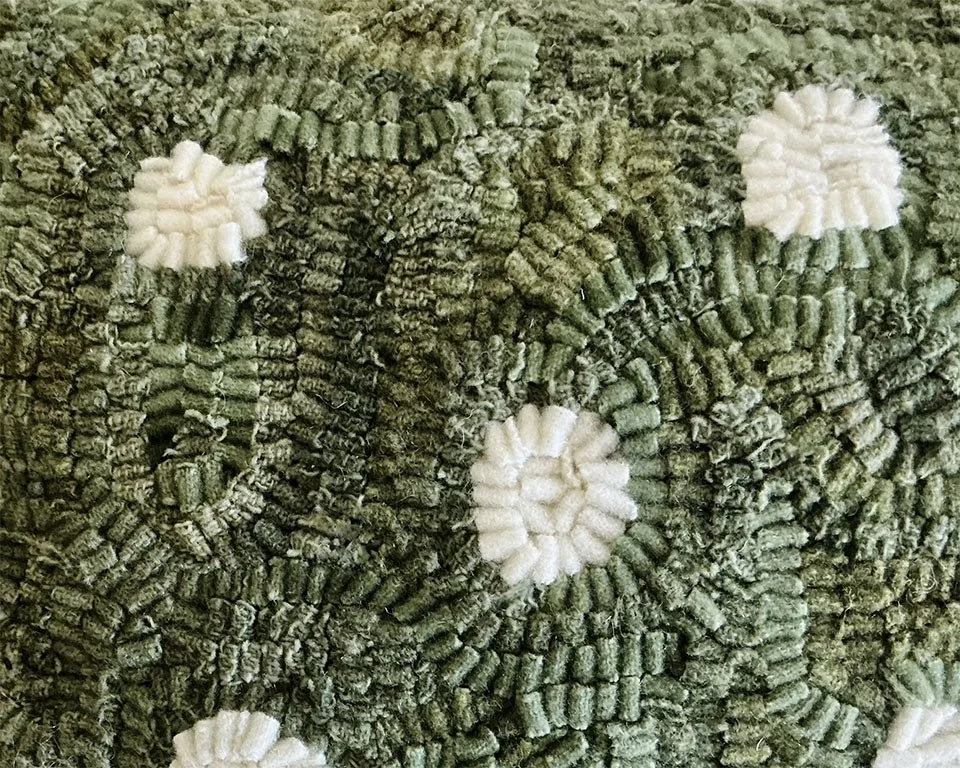 Detail of hand-hooked wool forming a dot motif on moss green ground.