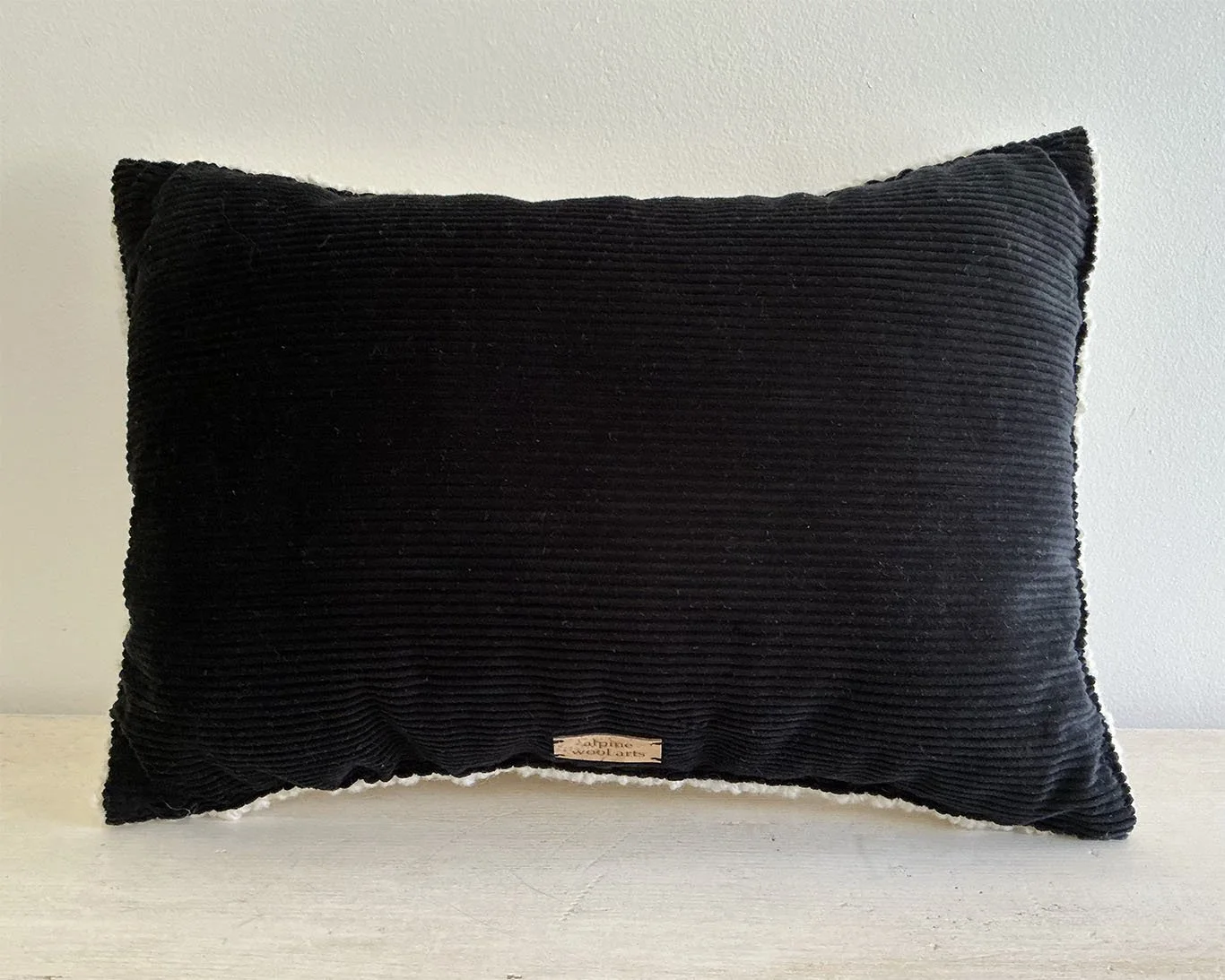 Back of pillow in black cotton corduroy fabric.