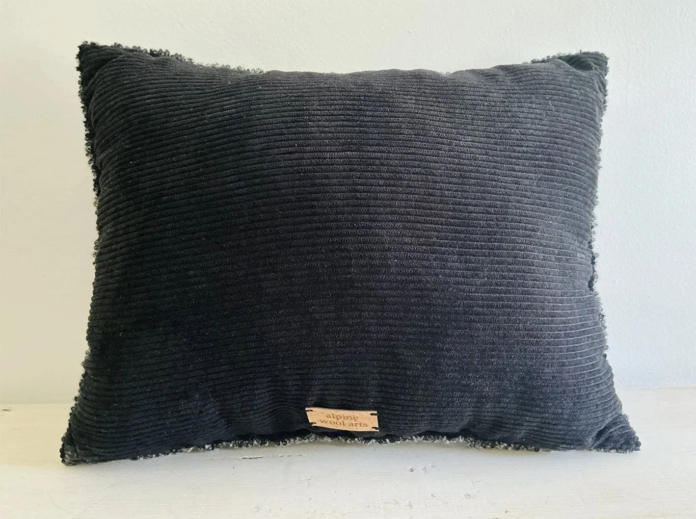 Back of pillow in charcoal cotton corduroy fabric.