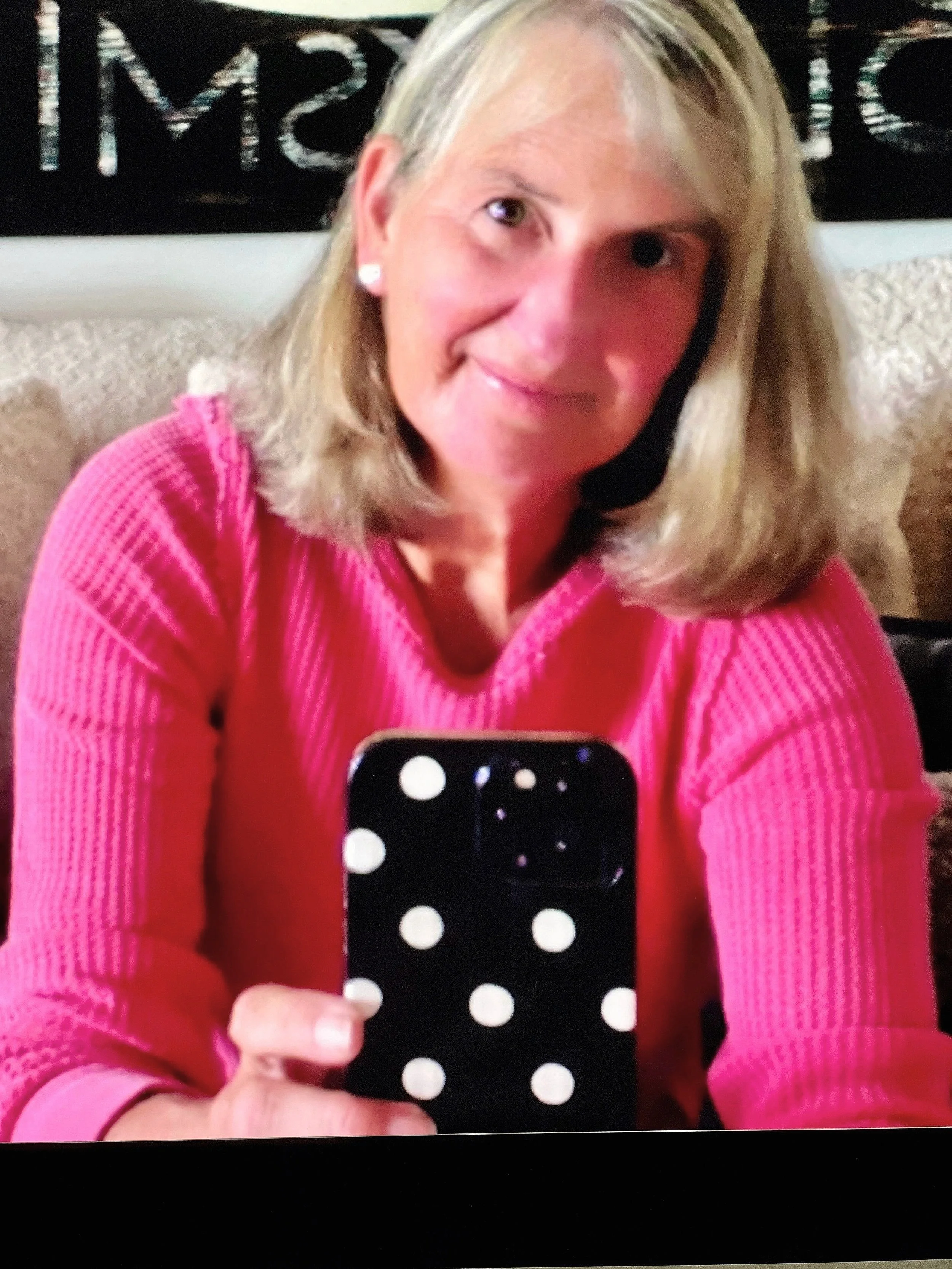 A woman with blonde hair wearing a pink sweater.