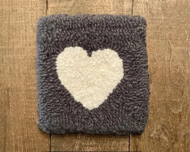 Hand-hooked wool panel in charcoal featuring centered ivory heart.