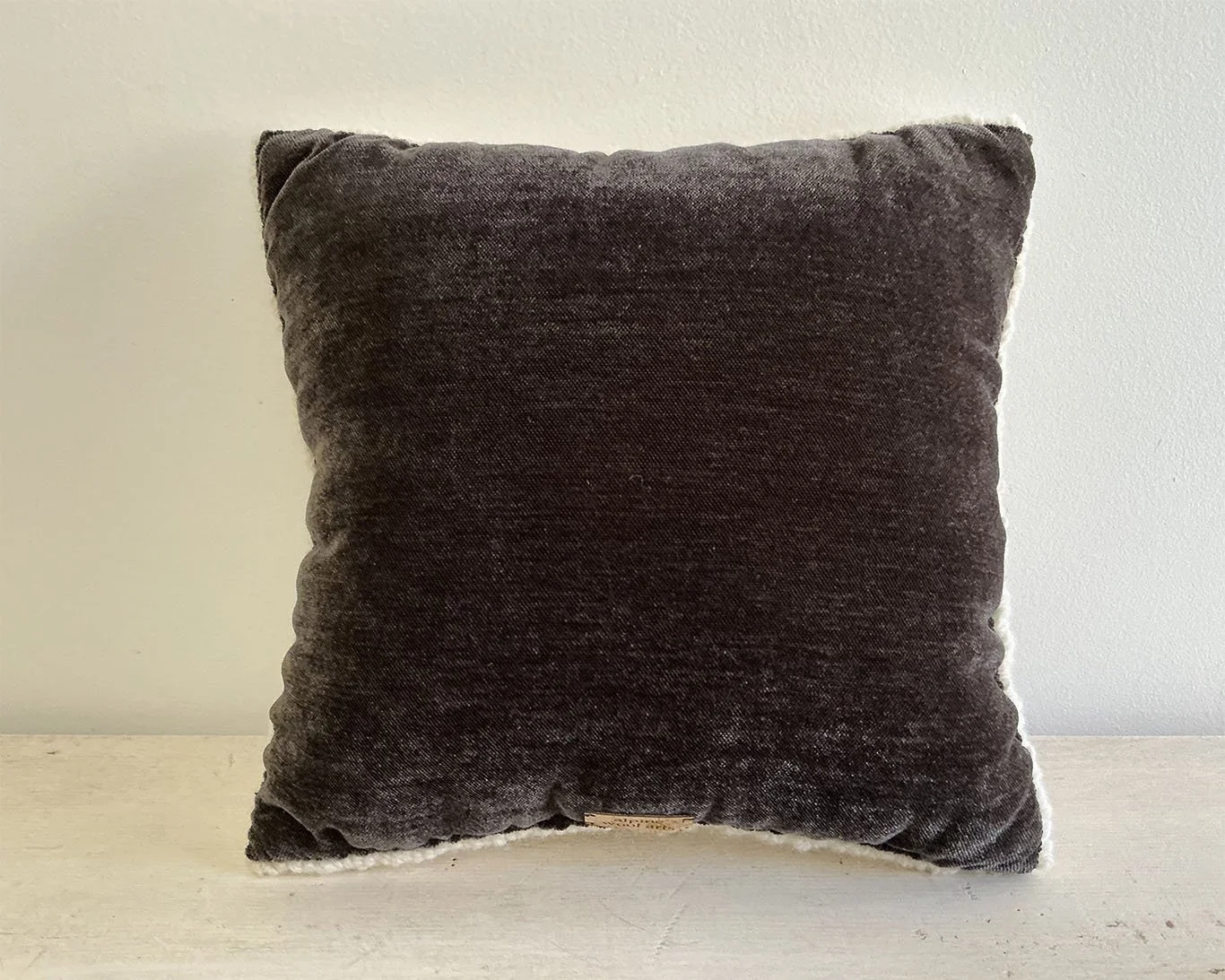 Back of pillow in dark brown cotton fabric.