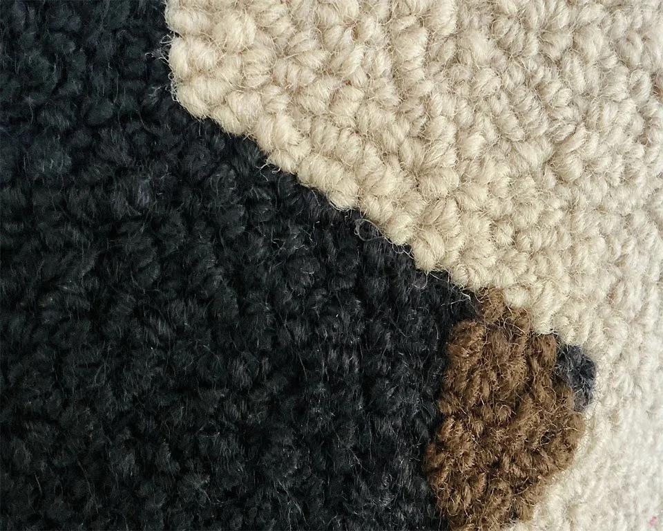 Detail of hand-hooked wool showing the bear against the natural ground.