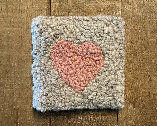 Hand-hooked wool panel with a blush-pink heart centered on a soft stone-gray wool ground.