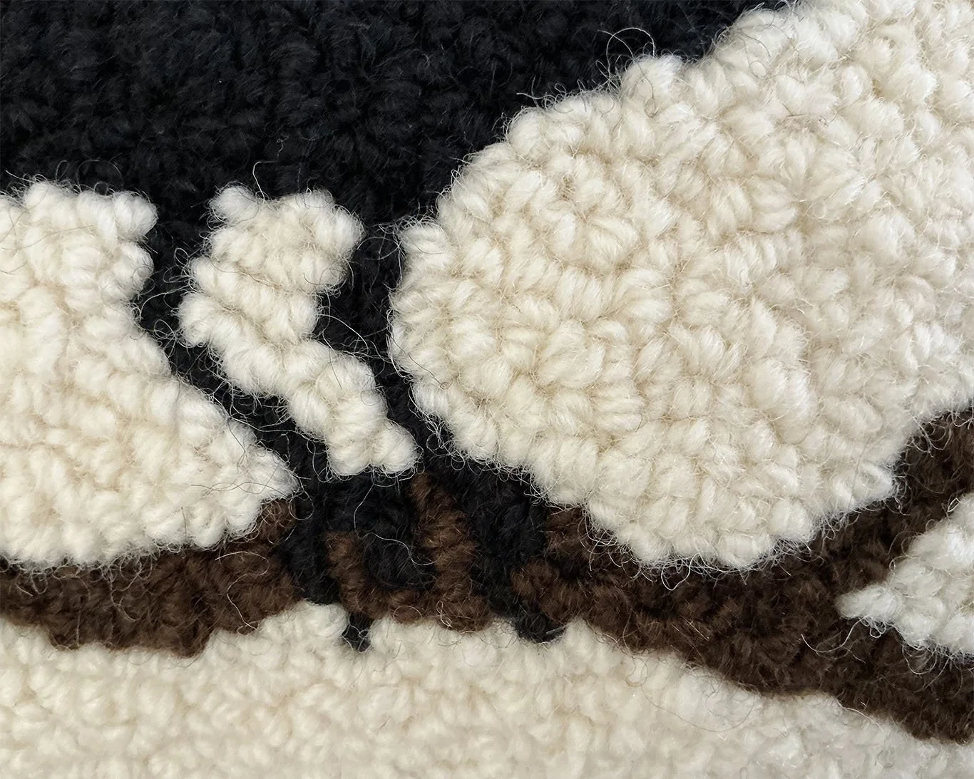 Detail of hand-hooked wool showing the raven and branch.